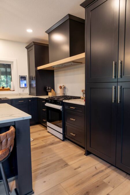 Full-height black pantry cabinets beside the cooking area by Crosby Fine Cabinetry Belle Plaine MN