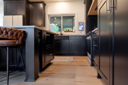 Black farmhouse sink beneath window with black shaker cabinets by Crosby Fine Cabinetry Belle Plaine MN