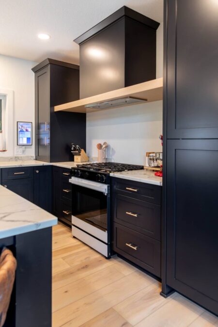 Custom black range hood with natural oak accent by Crosby Fine Cabinetry Belle Plaine MN